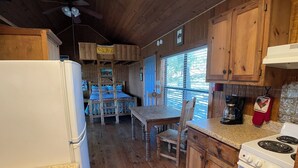 Een keuken in cottage-stijl met houten kastjes, een fornuis en een eethoek met een houten tafel en stoelen.