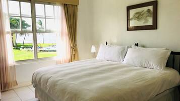 A hotel room with a large bed, a window with curtains, a bedside lamp, and a framed picture on the wall.