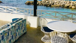 Un área de estar al aire libre con vista al mar y a la costa rocosa.