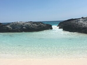 A beach with clear turquoise water, rocky formations, and a sandy shore. - Private 12 Acre Beachfront Home on a World Renowned Pink Sand Beach (Governors Harbour)