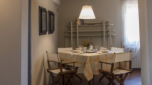 Un coin repas avec une table dressée pour quatre personnes, des chaises en bois et un luminaire suspendu.
