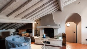 Un salon chaleureux avec des poutres apparentes, une cheminée et un coin salon confortable.