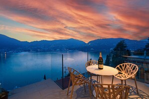 An outdoor terrace with a table and chairs overlooking a river and mountains. - Como Executive penthouse- 180 degree panoramic lake views by Italian Apartments. (Como)