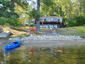 A lakeside cabin with a dock, a kayak, and a stone wall.
