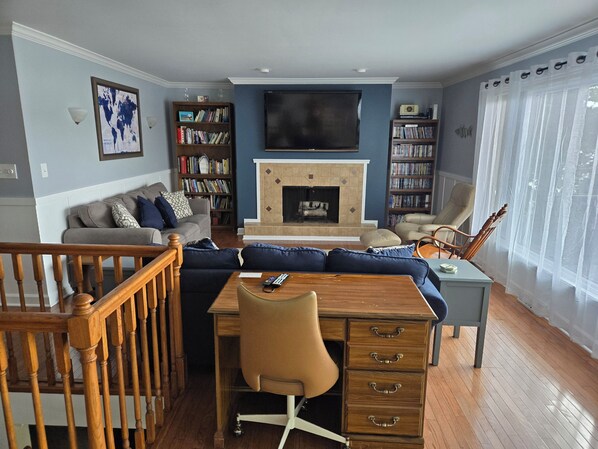 A living room with a fireplace, a sofa, a coffee table, a desk, and bookshelves.