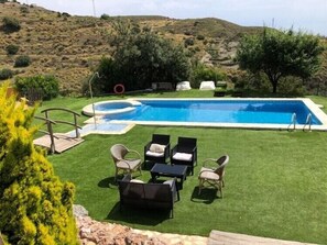 A rectangular swimming pool with a small hot tub and a wooden deck with lounge chairs. - Rural lodging Los Castros (Bédar)