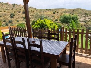 An outdoor patio with a table and chairs, surrounded by a wooden fence, overlooking a hilly landscape. - Rural lodging Los Castros (Bédar)