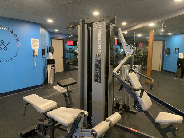 A gym with exercise equipment, a wall-mounted phone, and a mirror reflecting the equipment. - Studio Unit at Longhollow Point Inn (Galena)