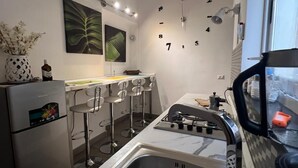 A modern kitchen with a stainless steel sink, a gas stove, and a refrigerator. There are bar stools and a clock on the wall. - APARTMENT, VACATION HOME CATANIA (Catania)