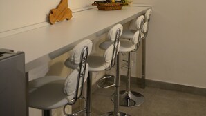 A modern kitchen with a white countertop, bar stools, and two large leaf-patterned wall art pieces. - APARTMENT, VACATION HOME CATANIA (Catania)