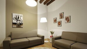 A living room with two sofas, a white rug, a lamp, and wall art. - Rialto twins house, in the center of the city (Venezia)