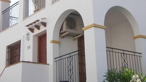 A multi-story building with white walls, arched balconies, and a tiled roof.