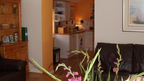 Un salon avec une table basse en bois, un canapé en cuir marron et un vase rempli de fleurs.