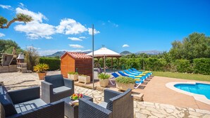 A patio with wicker furniture, a small wooden structure, and a pool area with lounge chairs.