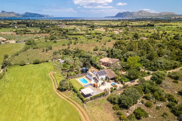 An aerial view of a property with a swimming pool, solar panels, and a large green field. - JESUS Finca for 5 with Pool in Pollensa (Port de Pollença)