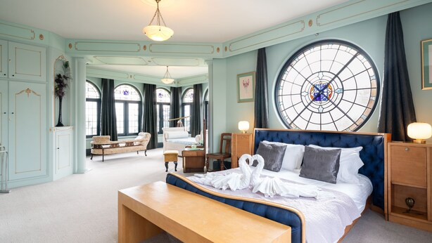 Ein geräumiges Schlafzimmer mit einem großen Bett, einem runden Fenster und einer Sitzbank.