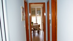 Un couloir qui se termine par un espace repas, comprenant une table et des chaises.