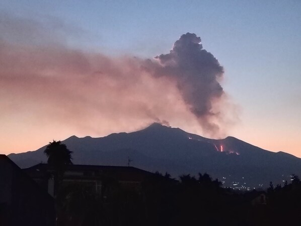 Une montagne où s'échappe de la fumée et où lèche un petit feu à sa base.