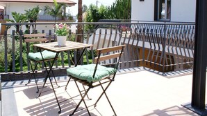 Un balcon avec une table et deux chaises, entouré d’une rambarde en métal.