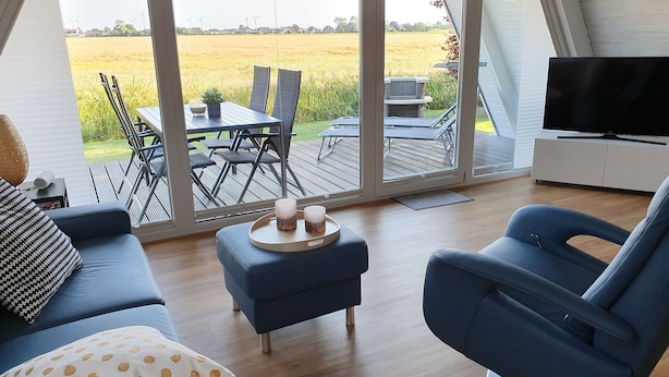 Uma sala de estar moderna com uma grande porta de vidro deslizante que dá para uma área de refeições ao ar livre.