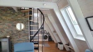 Quarto moderno no estilo loft com teto inclinado, escada em espiral, parede de pedra e um amplo claraboia.