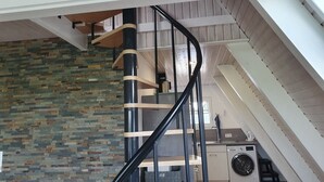 Um interior moderno com escada em espiral, parede de pedra e área de lavanderia.