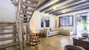 Un salon avec un escalier en bois, un canapé, un fauteuil à bascule et une grande fenêtre.