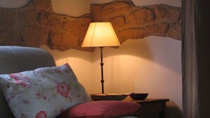 A bedroom with a bed, a nightstand, a lamp, and a stone headboard. - Holiday house for 2 pesons on small Estate with pool, near hot springs (Civitella Marittima)
