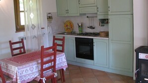 A kitchen with light green cabinets, a dining table with chairs, a stove, and a small oven. - Holiday house for 2 pesons on small Estate with pool, near hot springs (Civitella Marittima)