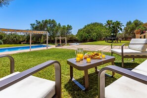 Un patio trasero con piscina, mobiliario exterior y una mesa con comida y bebidas.