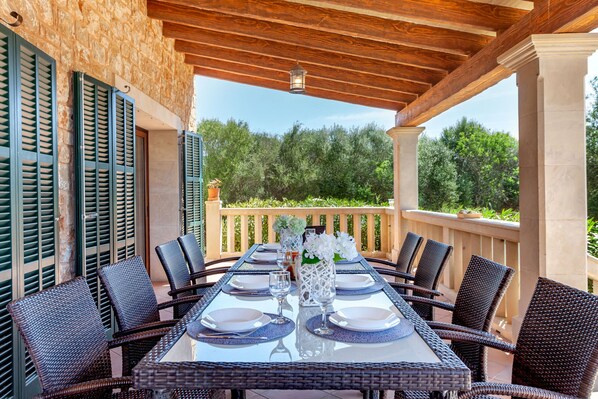 An outdoor dining area with a table set for four, surrounded by wicker chairs, under a wooden pergola with a view of greenery. - Bassa Seca by dracmallorca (Santanyi)