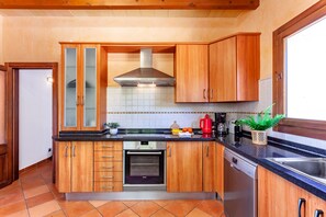 Una cocina moderna con armarios de madera, extractor de acero inoxidable y horno empotrado.