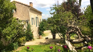 A rustic stone building with a garden featuring vibrant flowers and a variety of plants.