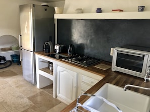 A compact kitchen with a refrigerator, stove, toaster, and sink. - Charming Magnanerie with swimming pool and pétanque court in an idyllic setting (Bonnieux)