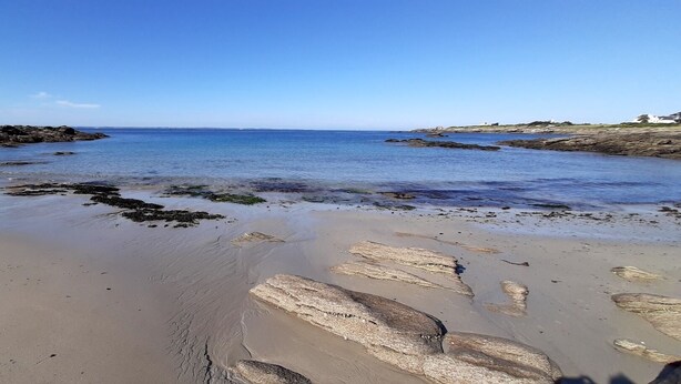 Una playa con rocas grandes y agua tranquila.