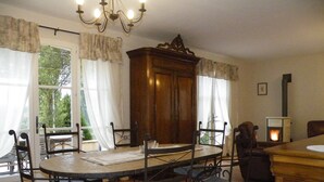 A dining area with a round table, six chairs, a wooden cabinet, and a fireplace. - Beautiful house with private heated infinity pool 16 km from Uzes (Connaux)