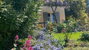 A house with a tiled roof, surrounded by lush greenery and flowering plants. - Beautiful house with private heated infinity pool 16 km from Uzes (Connaux)