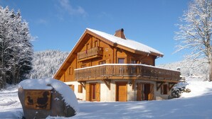 Una cabaña de madera con balcón, rodeada de árboles cubiertos de nieve.