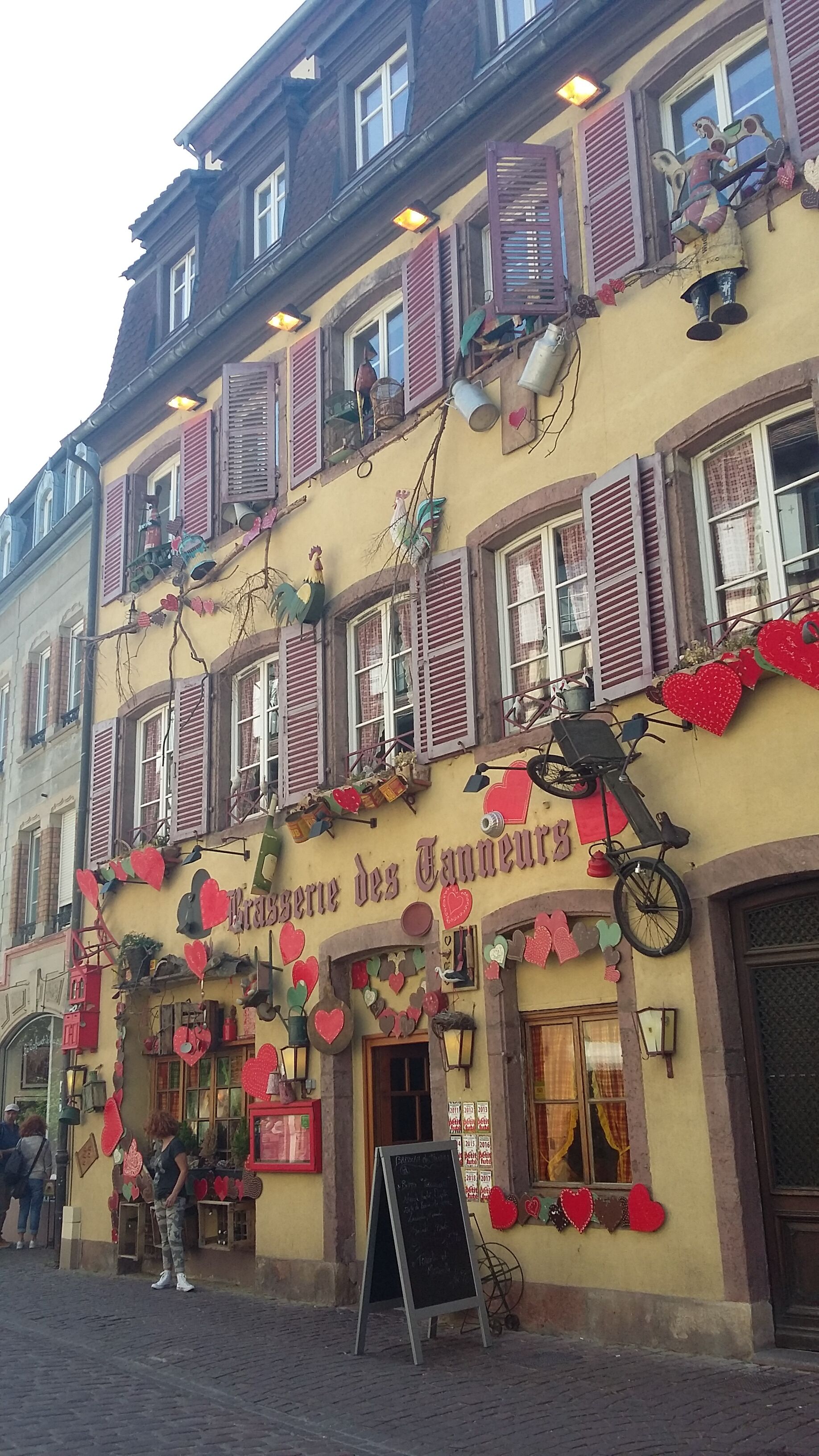Un bâtiment sur lequel on peut lire l’inscription « La Ferme des Couverts » et qui est décoré de motifs en forme de cœur.