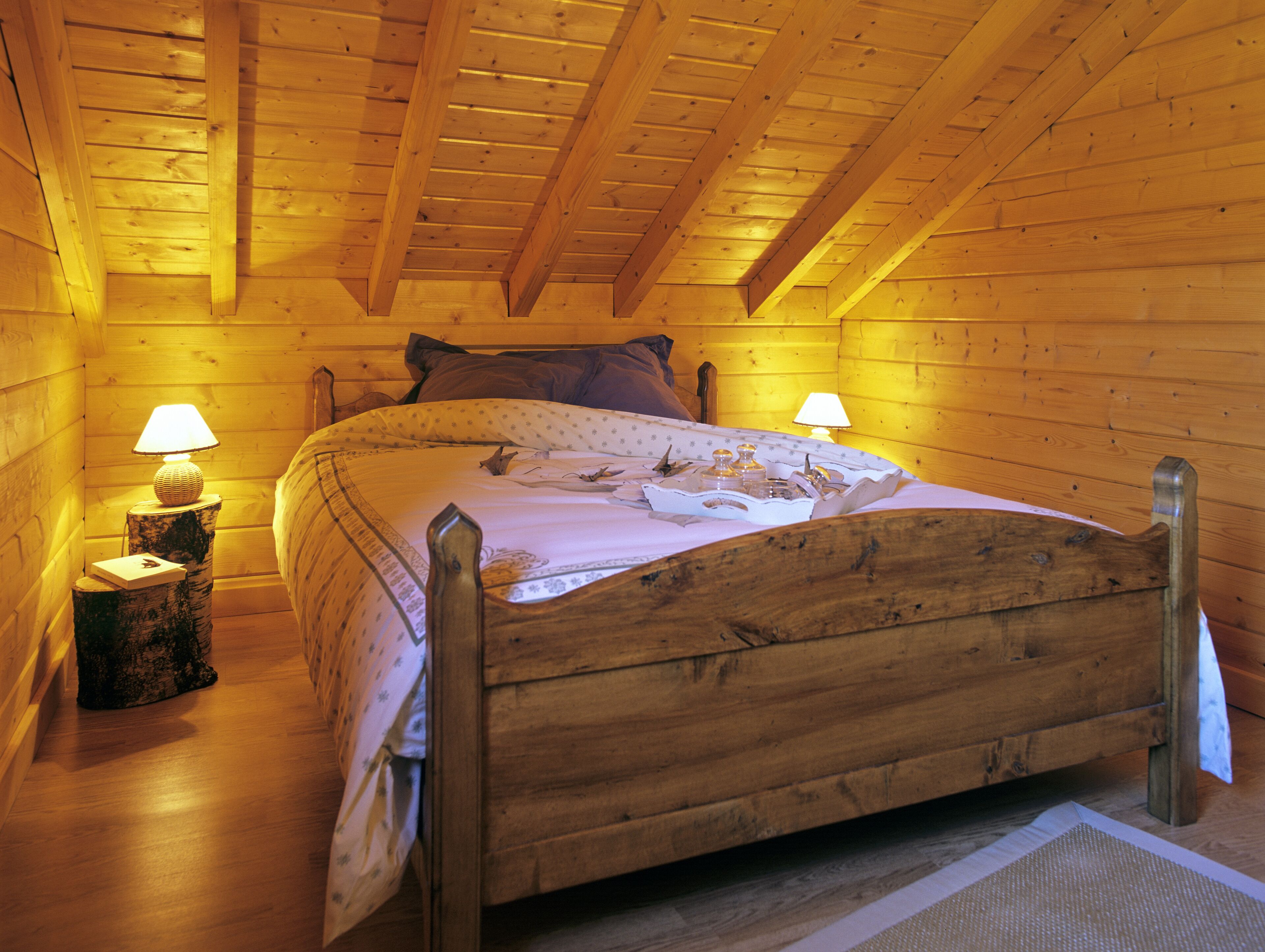 Un lit en bois dans une cabane, avec deux lampes de chevet.