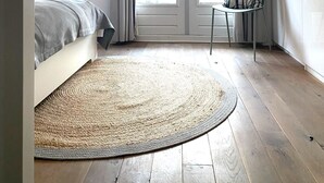 Une chambre à coucher avec un lit, une chaise, un tapis rond et une porte avec des rideaux.