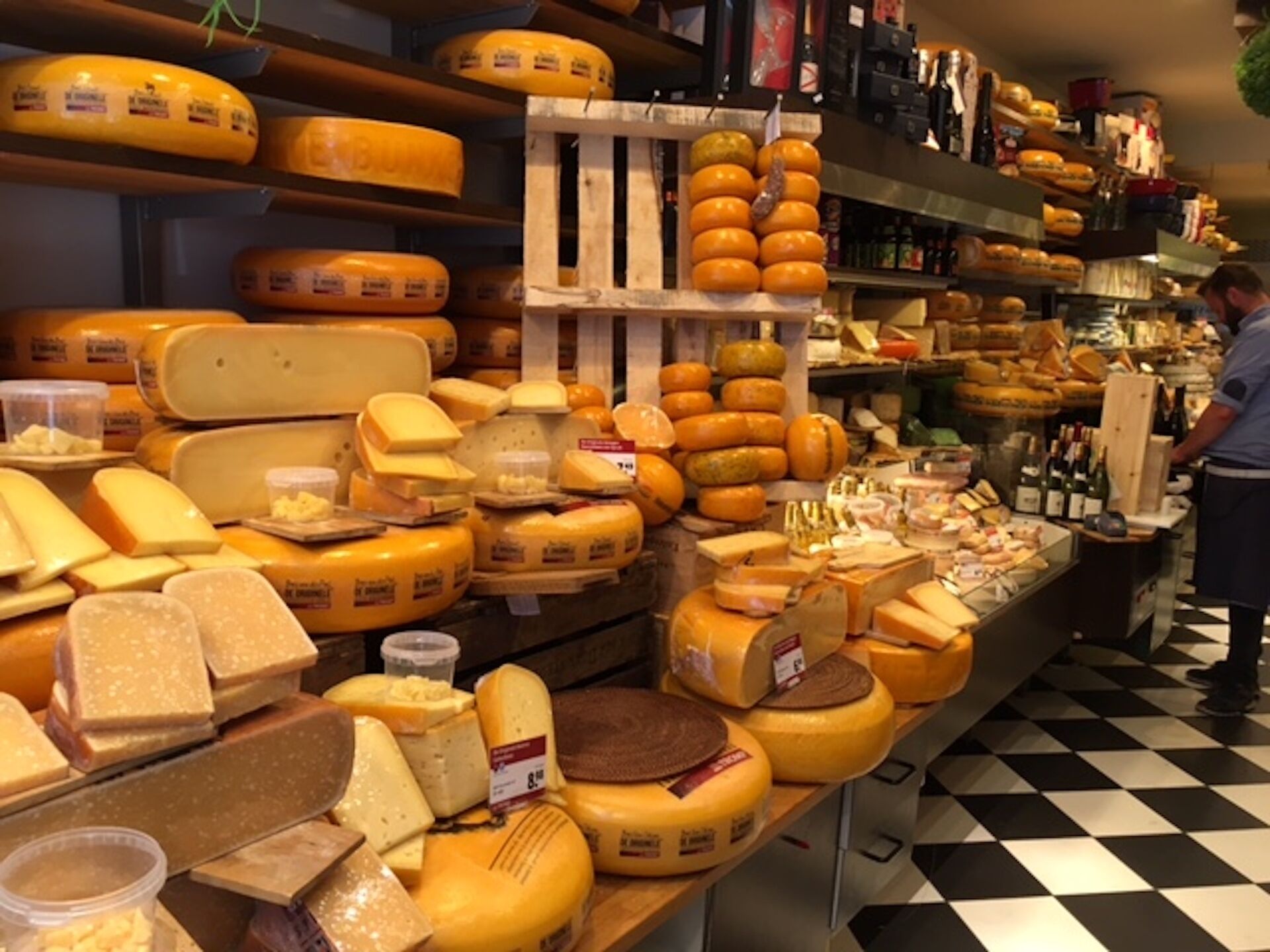 Un présentoir à fromages dans un magasin, avec différents types de fromages exposés sur des étagères et des tables.