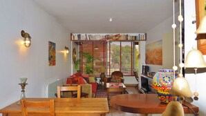 Una sala de estar acogedora con una mesa de madera, sillas, un sofá y una estantería llena de libros.
