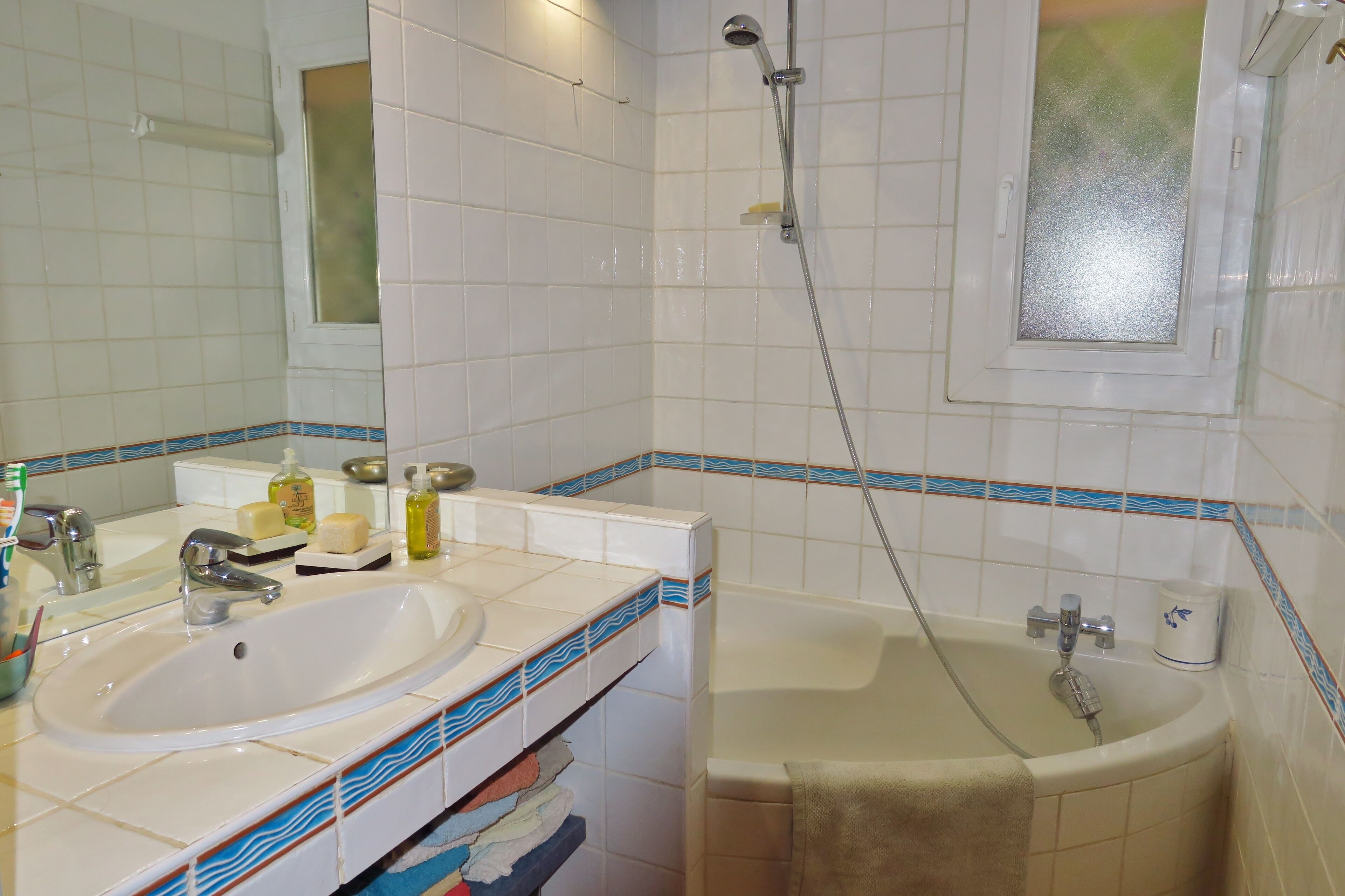 A bathroom with a sink, mirror, and bathtub.