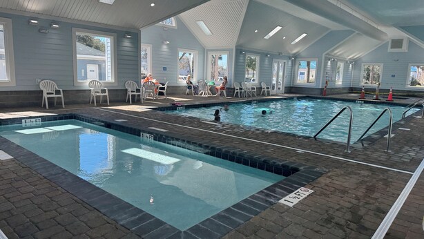 Una piscina interior con agua cristalina, paredes de azulejos y suelo de ladrillo.