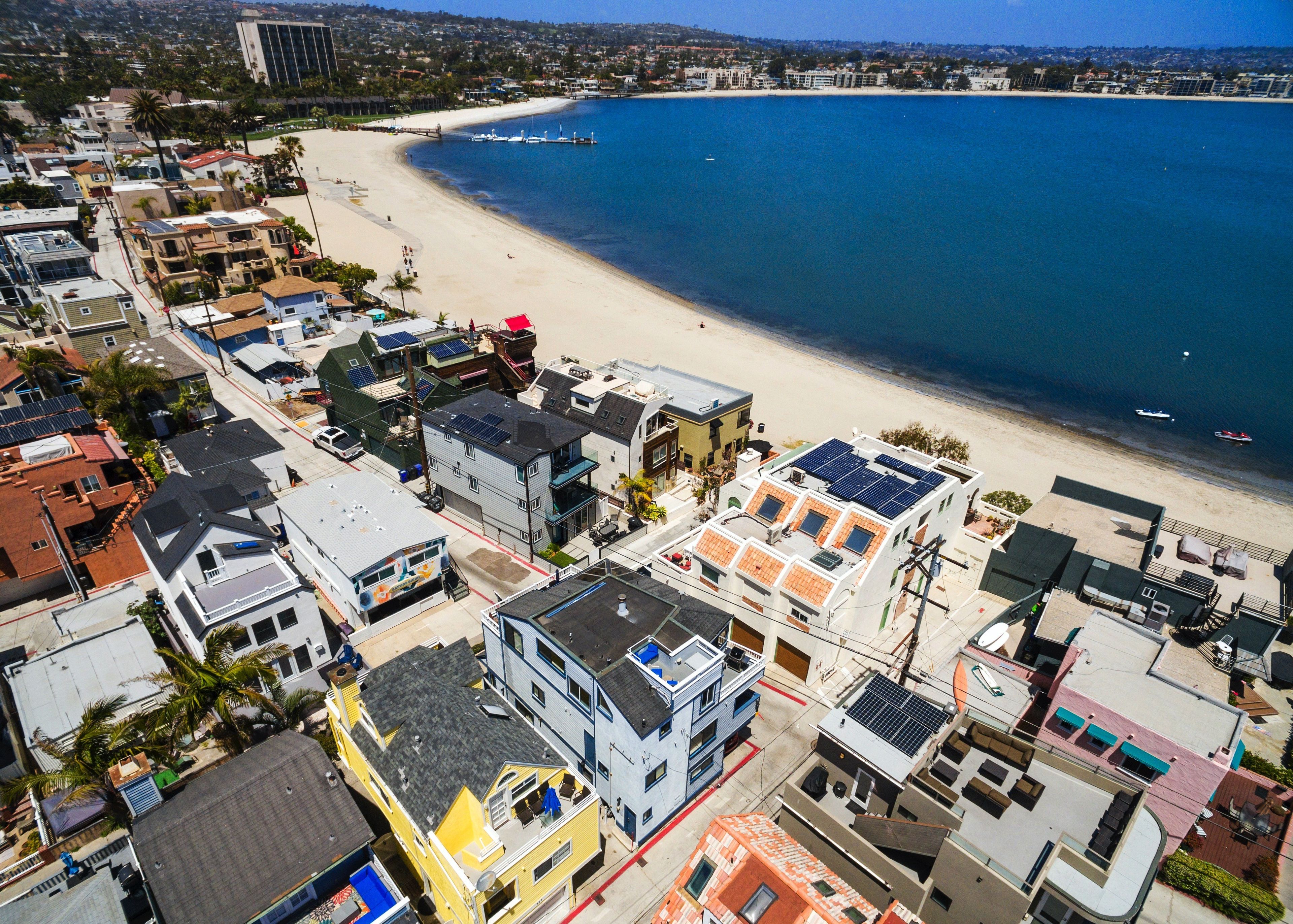 A coastal residential area with buildings, a beach, and boats.