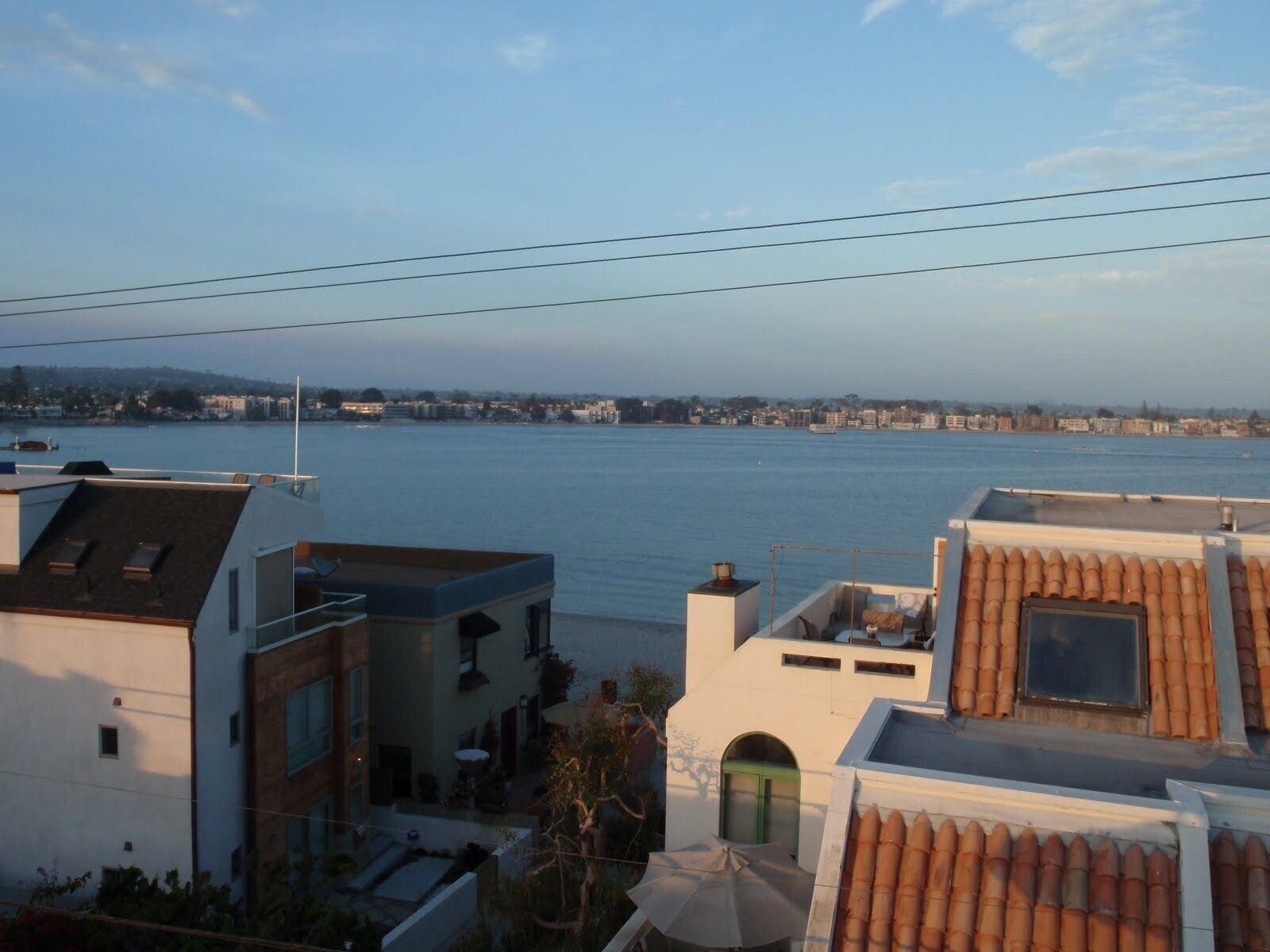 Zona residencial con vista a una gran masa de agua, probablemente un lago o río, y un horizonte urbano lejano.