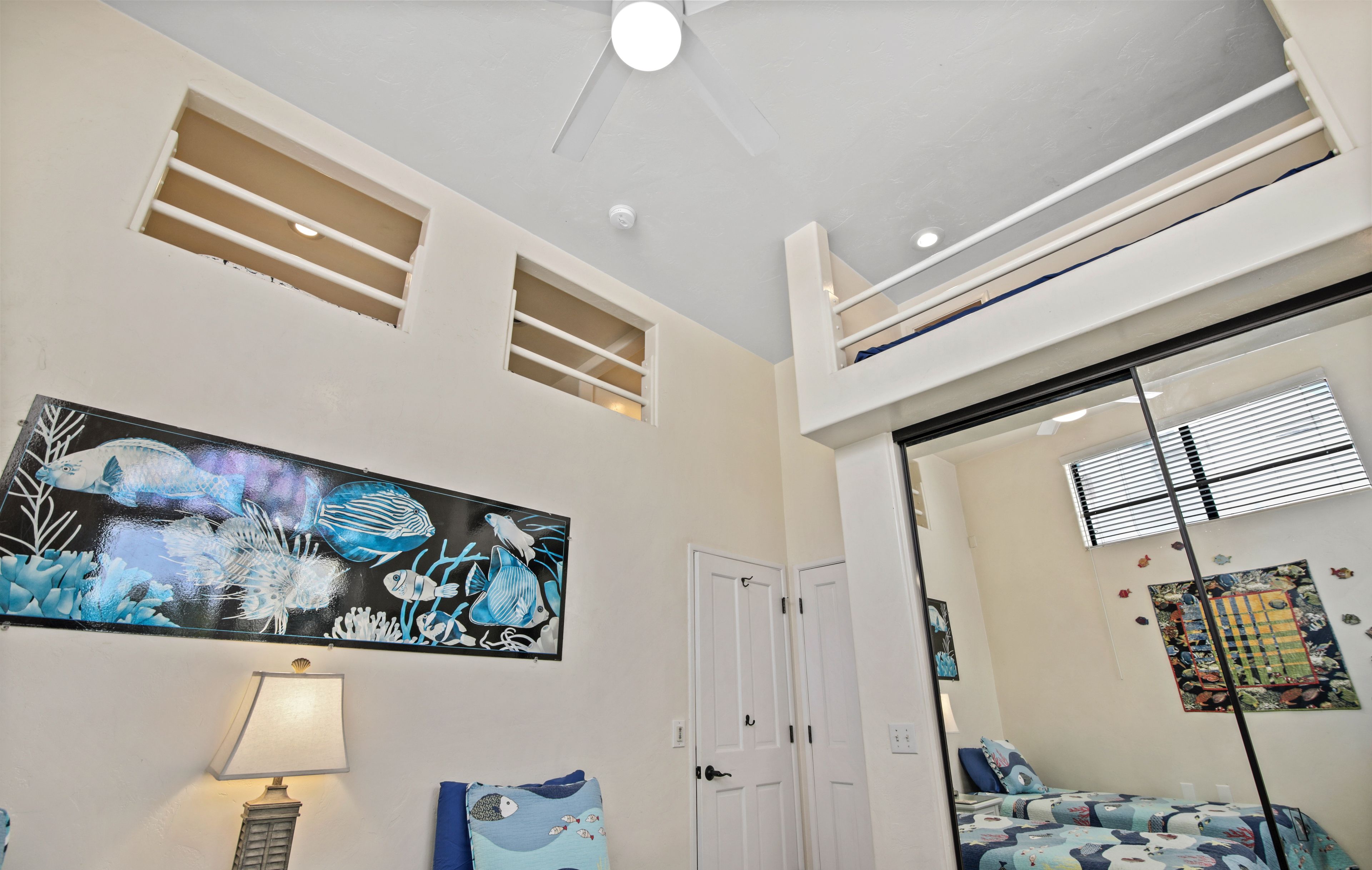 A room with a bed, a painting, a lamp, and a ceiling fan.