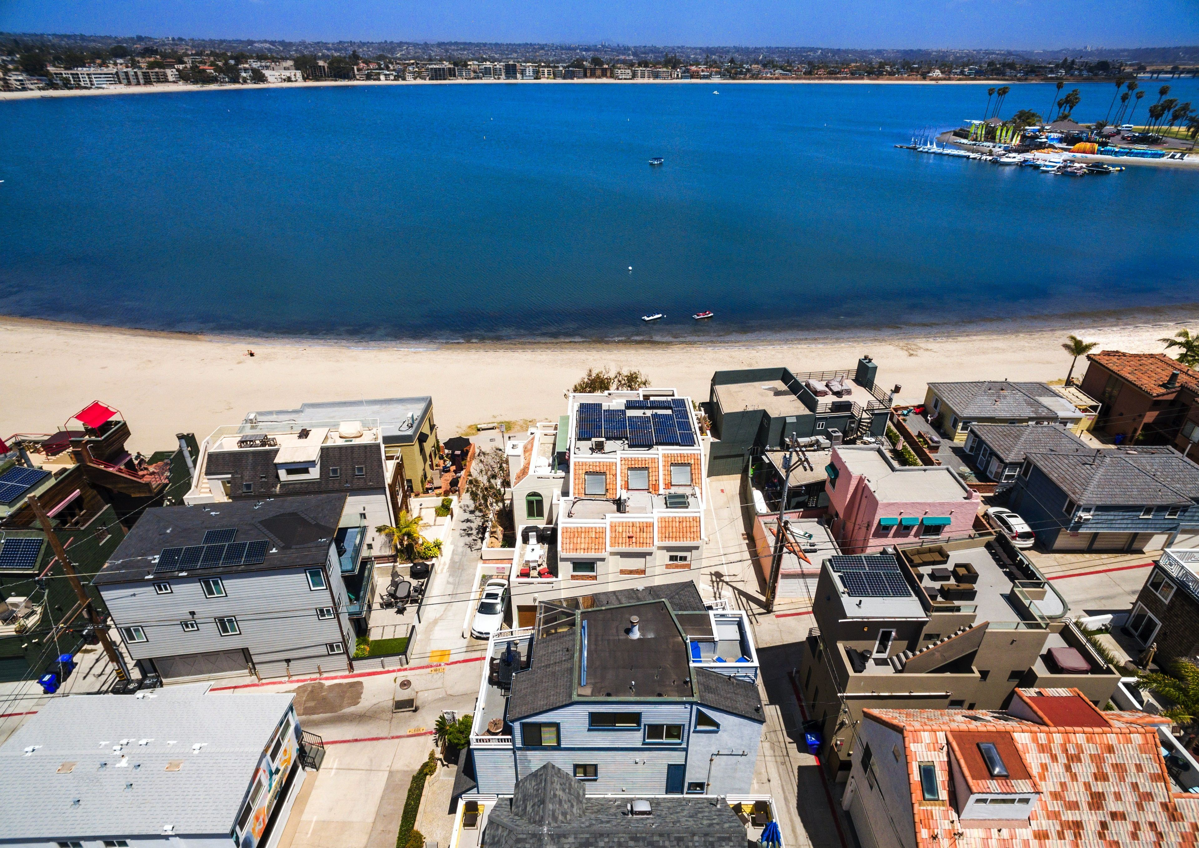 A coastal residential area with buildings, a beach, and a marina.