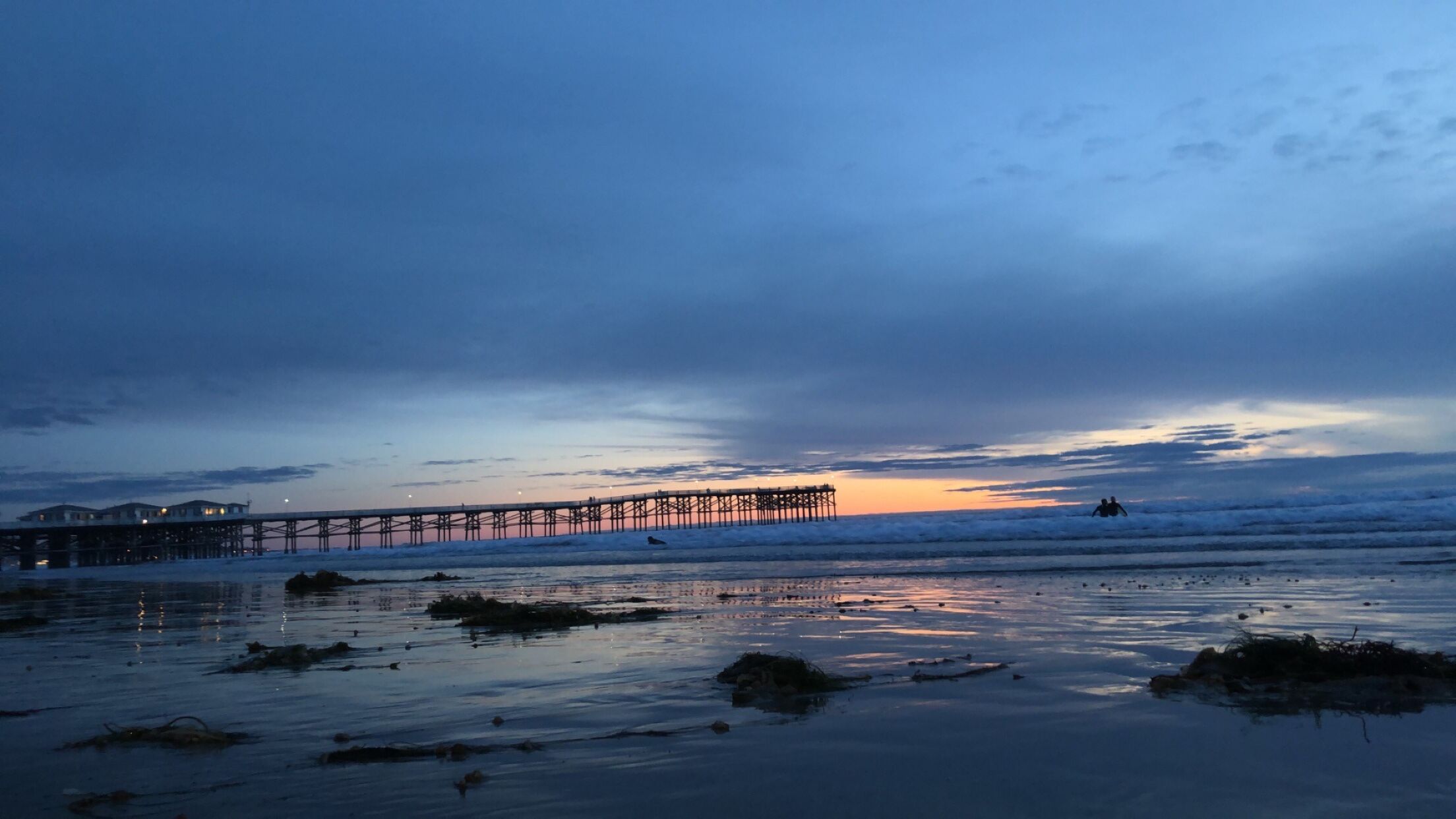 Une jetée qui s’avance dans l’eau, avec un coucher de soleil en arrière-plan.